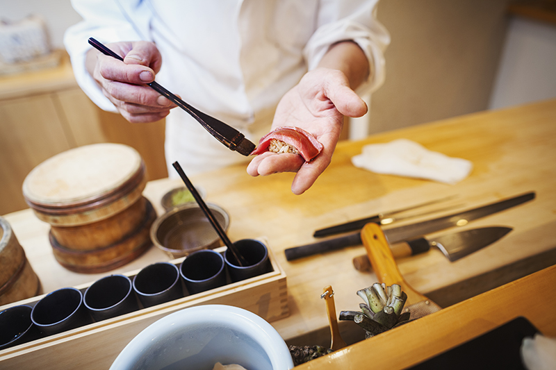 寿司を握る,日本,小さな業務用厨房で働く板前、魚にタレを塗りながら寿司を握る。