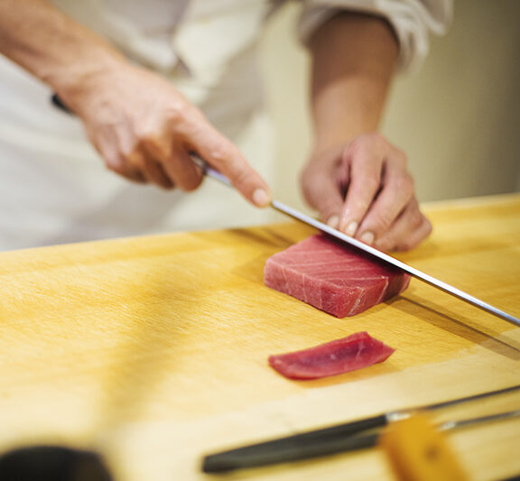 寿司を握る,日本,小さな業務用厨房で働く板前さん、寿司を握るために大きな包丁で魚を切る板前さん。